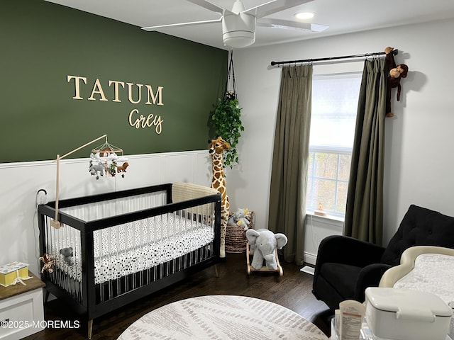 bedroom with a nursery area and wood finished floors