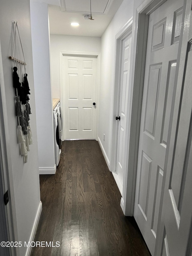 hall featuring washer and dryer, baseboards, attic access, and dark wood finished floors