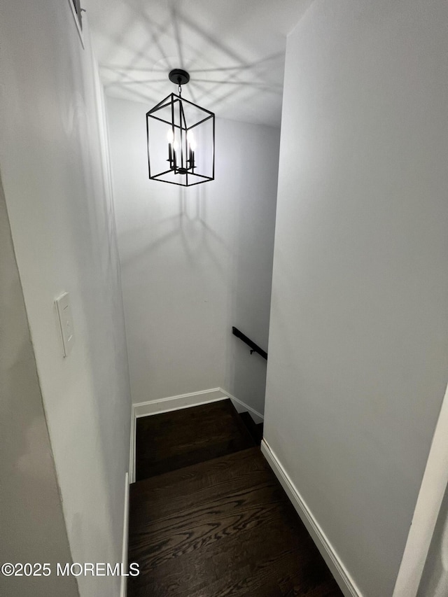 stairs with a chandelier, baseboards, and wood finished floors