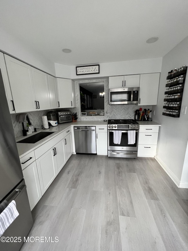 kitchen featuring light wood finished floors, white cabinets, and stainless steel appliances