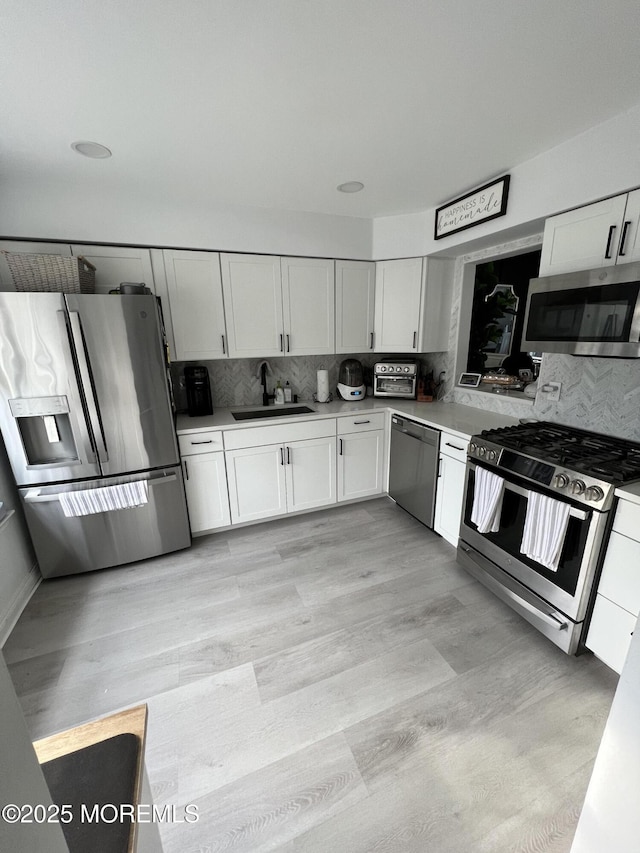 kitchen featuring a sink, tasteful backsplash, appliances with stainless steel finishes, and white cabinetry