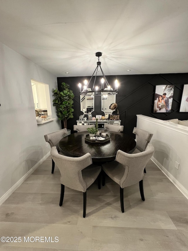 dining area with light wood-style floors, baseboards, and a chandelier