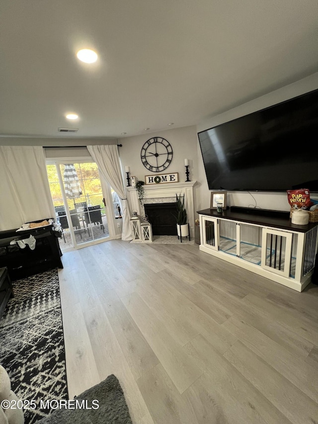 living room with recessed lighting, visible vents, wood finished floors, and a fireplace