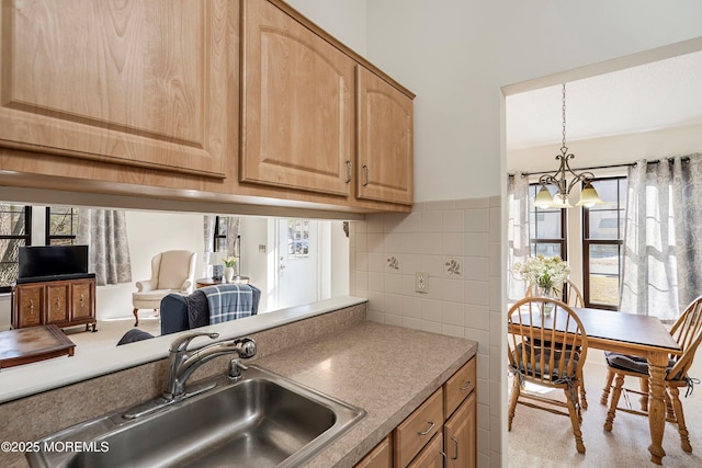 kitchen featuring sink, hanging light fixtures, light brown cabinets, a notable chandelier, and decorative backsplash