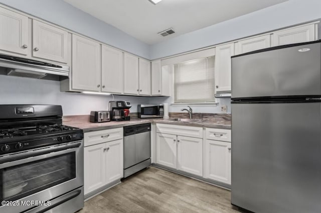 kitchen with white cabinetry, sink, stainless steel appliances, and light hardwood / wood-style floors