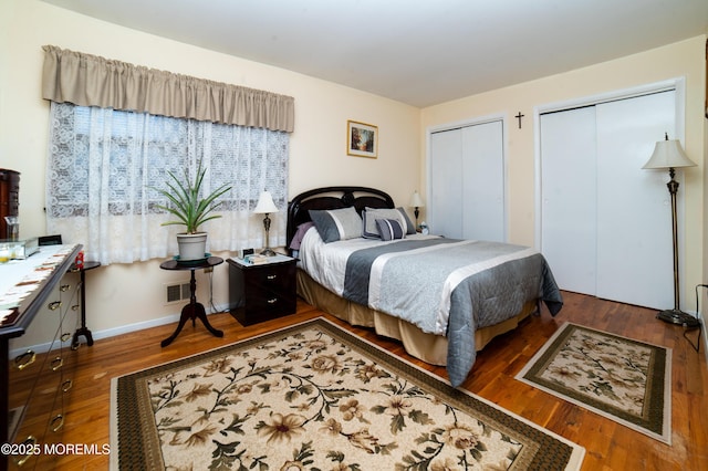 bedroom featuring multiple closets and dark hardwood / wood-style floors