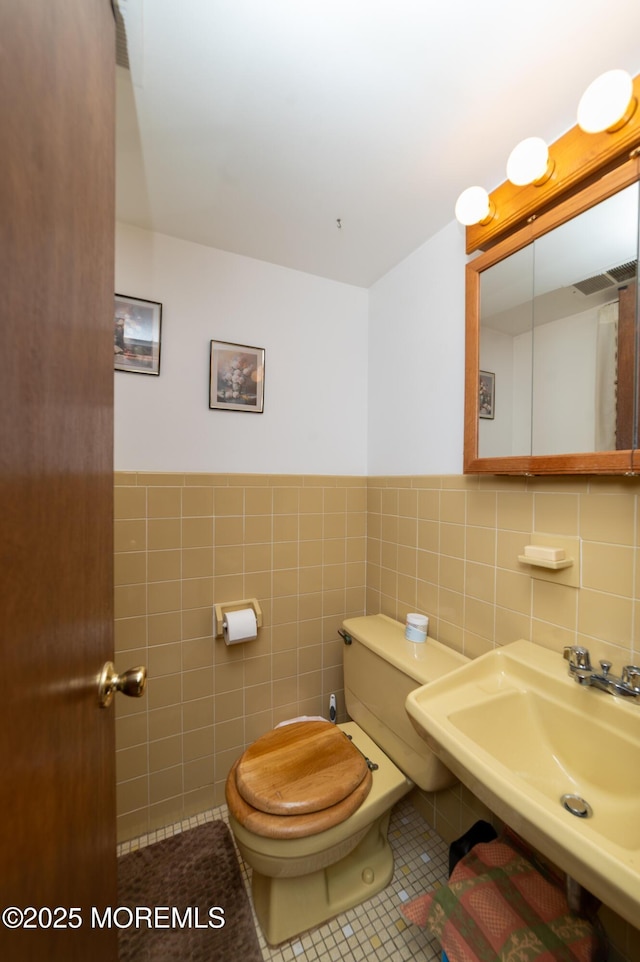 bathroom featuring tile patterned flooring, sink, tile walls, and toilet