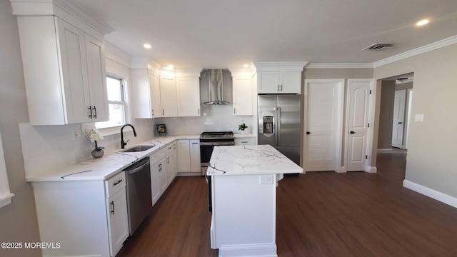 kitchen with wall chimney exhaust hood, sink, a center island, appliances with stainless steel finishes, and white cabinets