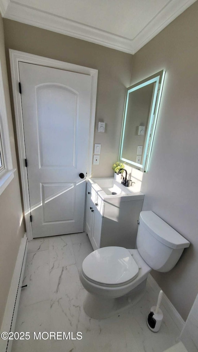 bathroom with baseboard heating, vanity, crown molding, and toilet