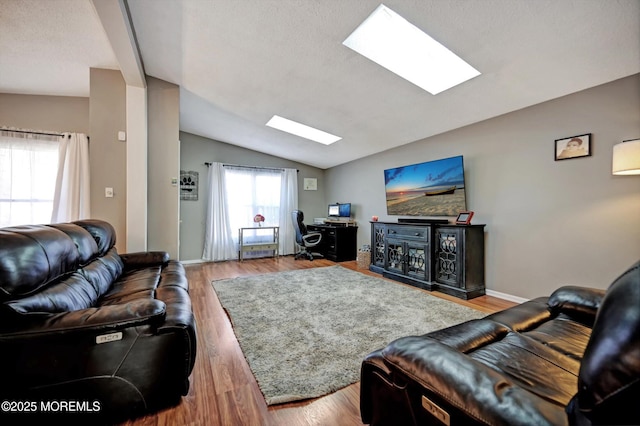 living room featuring lofted ceiling with skylight, wood finished floors, and baseboards