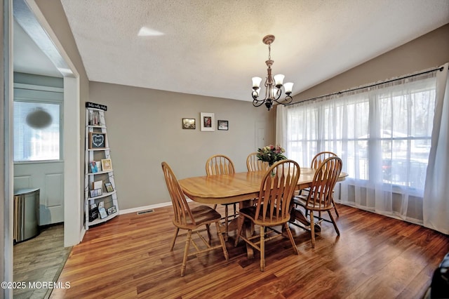 dining room with lofted ceiling, visible vents, light wood-style floors, a textured ceiling, and a chandelier