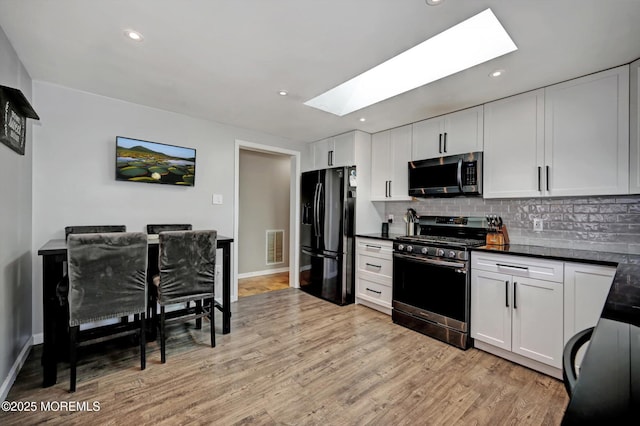 kitchen featuring tasteful backsplash, dark countertops, stainless steel appliances, light wood-style floors, and recessed lighting