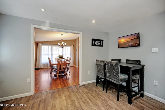 dining space featuring baseboards, recessed lighting, wood finished floors, and an inviting chandelier