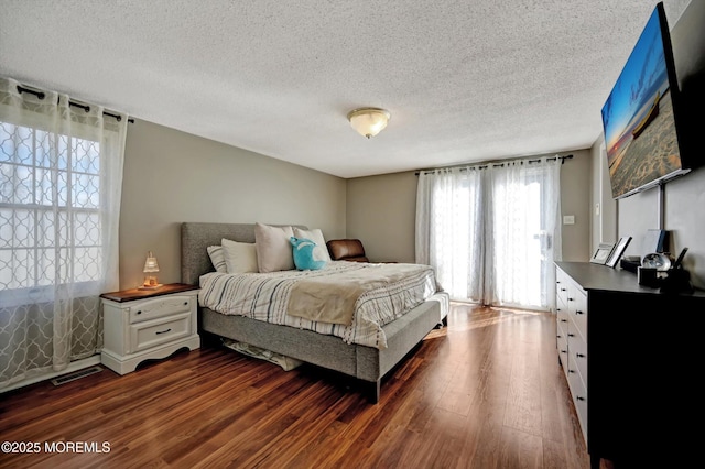 bedroom featuring visible vents, dark wood finished floors, and a textured ceiling