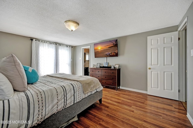 bedroom featuring a textured ceiling, wood finished floors, and baseboards