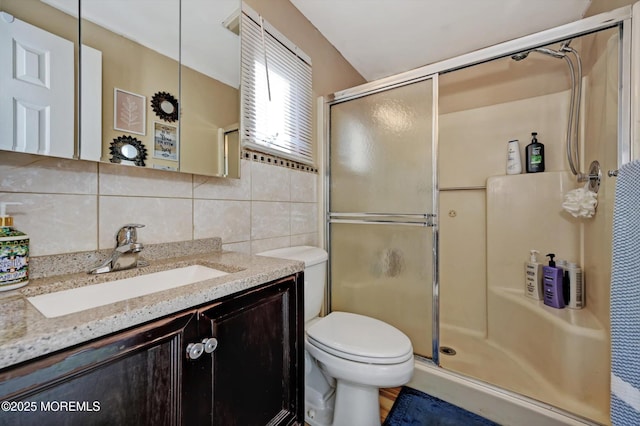 bathroom featuring toilet, a stall shower, tile walls, and vanity