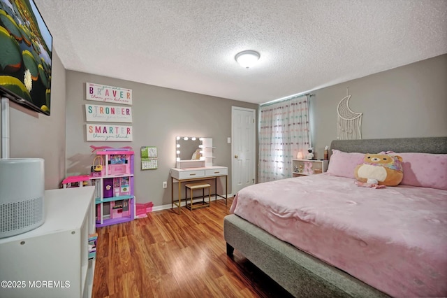 bedroom with a textured ceiling, baseboards, and wood finished floors