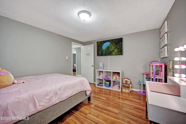 bedroom featuring a textured ceiling, baseboards, and wood finished floors