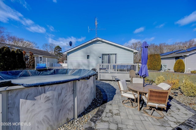 rear view of property with a fenced in pool, outdoor dining space, a patio area, fence, and a deck