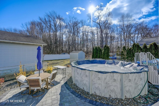 view of pool featuring a patio area, fence, a shed, a covered pool, and an outdoor structure