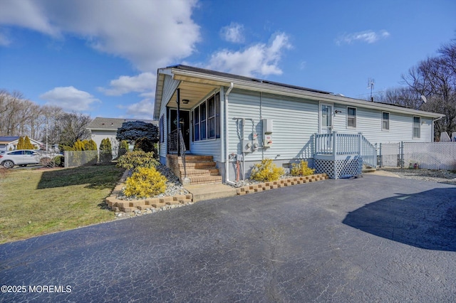 view of front of home featuring driveway, fence, and a front lawn