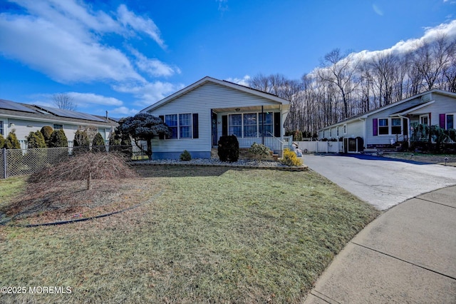 view of front facade featuring driveway, fence, and a front yard