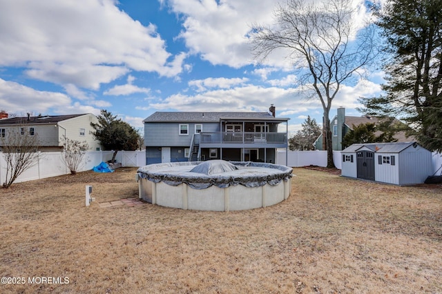 back of house featuring a lawn, a covered pool, and a storage unit