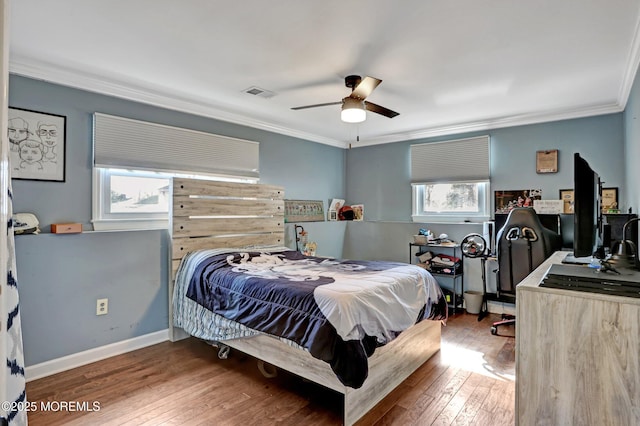 bedroom featuring multiple windows, hardwood / wood-style floors, ornamental molding, and ceiling fan