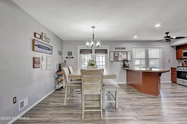 dining space featuring ceiling fan with notable chandelier, plenty of natural light, and light hardwood / wood-style floors