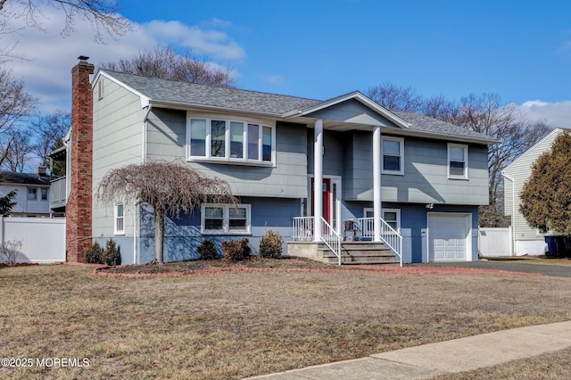 raised ranch featuring a garage and a front yard