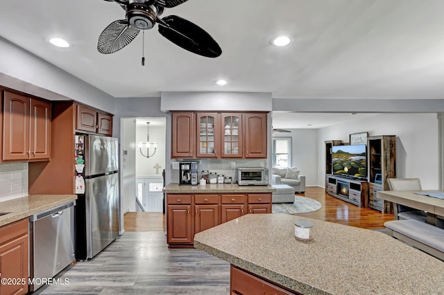 kitchen featuring tasteful backsplash, ceiling fan with notable chandelier, light hardwood / wood-style floors, and appliances with stainless steel finishes