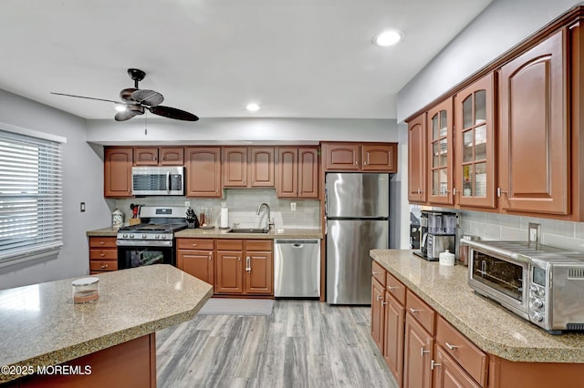 kitchen featuring tasteful backsplash, sink, ceiling fan, stainless steel appliances, and light hardwood / wood-style flooring