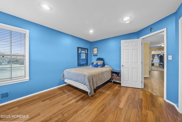 bedroom with baseboards, visible vents, wood finished floors, and recessed lighting