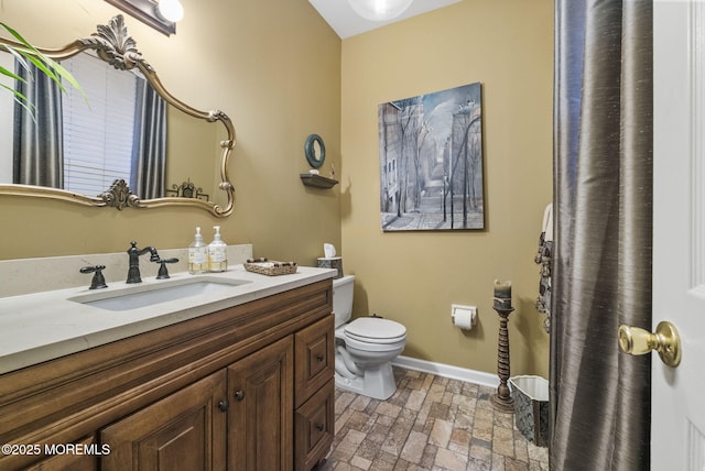 bathroom featuring toilet, baseboards, and vanity