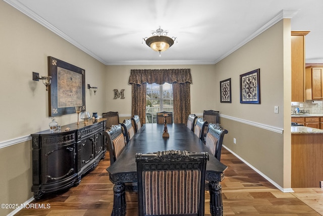 dining room featuring crown molding, baseboards, and wood finished floors