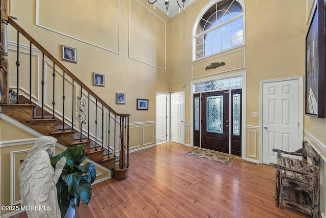 foyer with a wainscoted wall, stairway, wood finished floors, and a decorative wall