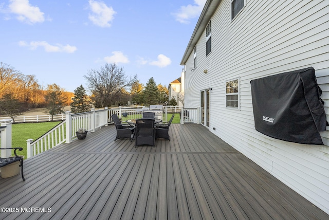 wooden deck with outdoor dining space and a yard