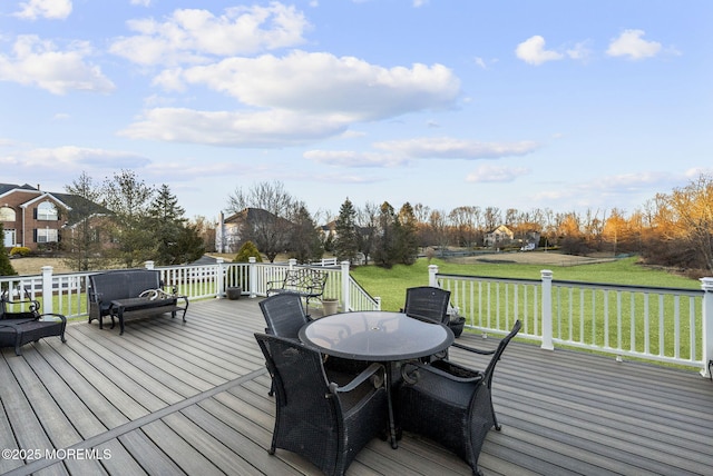 wooden terrace with outdoor dining area and a lawn