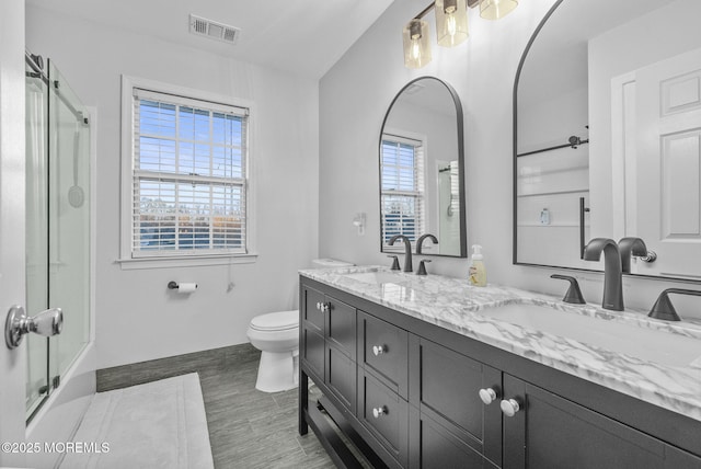 full bathroom featuring toilet, double vanity, a sink, and visible vents