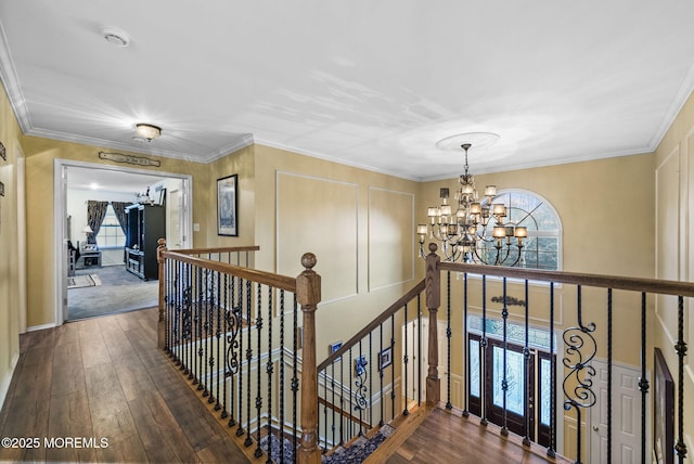 corridor featuring ornamental molding, a notable chandelier, and an upstairs landing