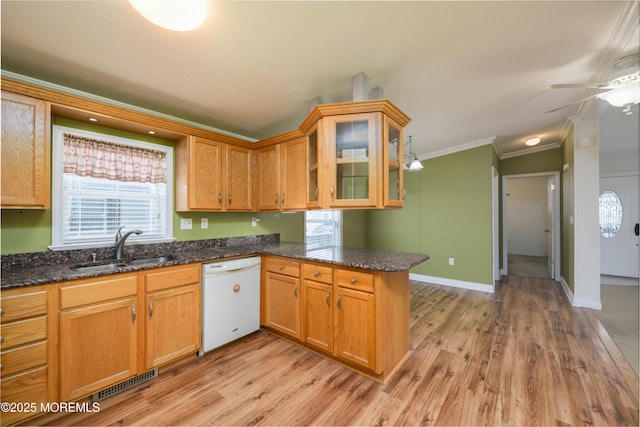 kitchen with sink, ornamental molding, dishwasher, kitchen peninsula, and dark stone counters