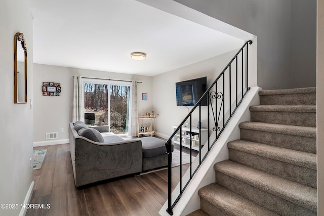 staircase with wood finished floors, visible vents, and baseboards