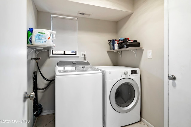 laundry room featuring light tile patterned floors, laundry area, visible vents, baseboards, and washing machine and clothes dryer