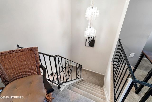 stairway with baseboards, carpet flooring, and a notable chandelier