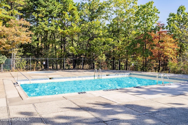 community pool with a patio area and fence