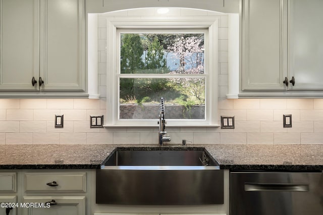 kitchen featuring backsplash, dishwasher, sink, and dark stone countertops