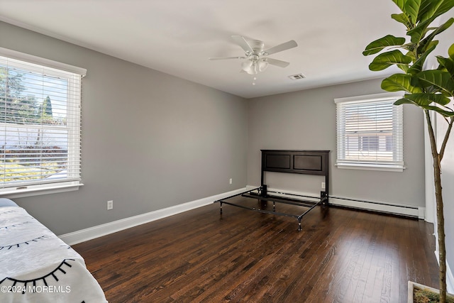 unfurnished bedroom with ceiling fan, dark hardwood / wood-style floors, and a baseboard heating unit