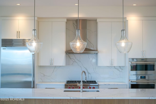 kitchen featuring stainless steel appliances, white cabinetry, light stone counters, and decorative light fixtures