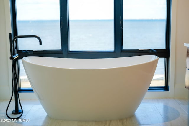 bathroom featuring tile patterned flooring, a water view, and a tub to relax in