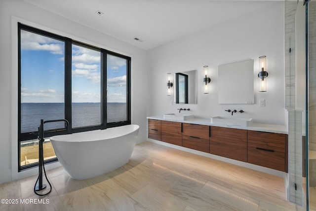 bathroom featuring vanity, plenty of natural light, a tub, and a water view